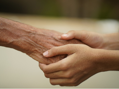Una persona jove agafa la mà a una persona gran