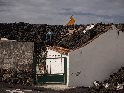 Fotografia d'un home assegut sobre una teulada coberta de terra i runa, del treball “Oblit polític, silenci mediàtic” de Víctor Cabo