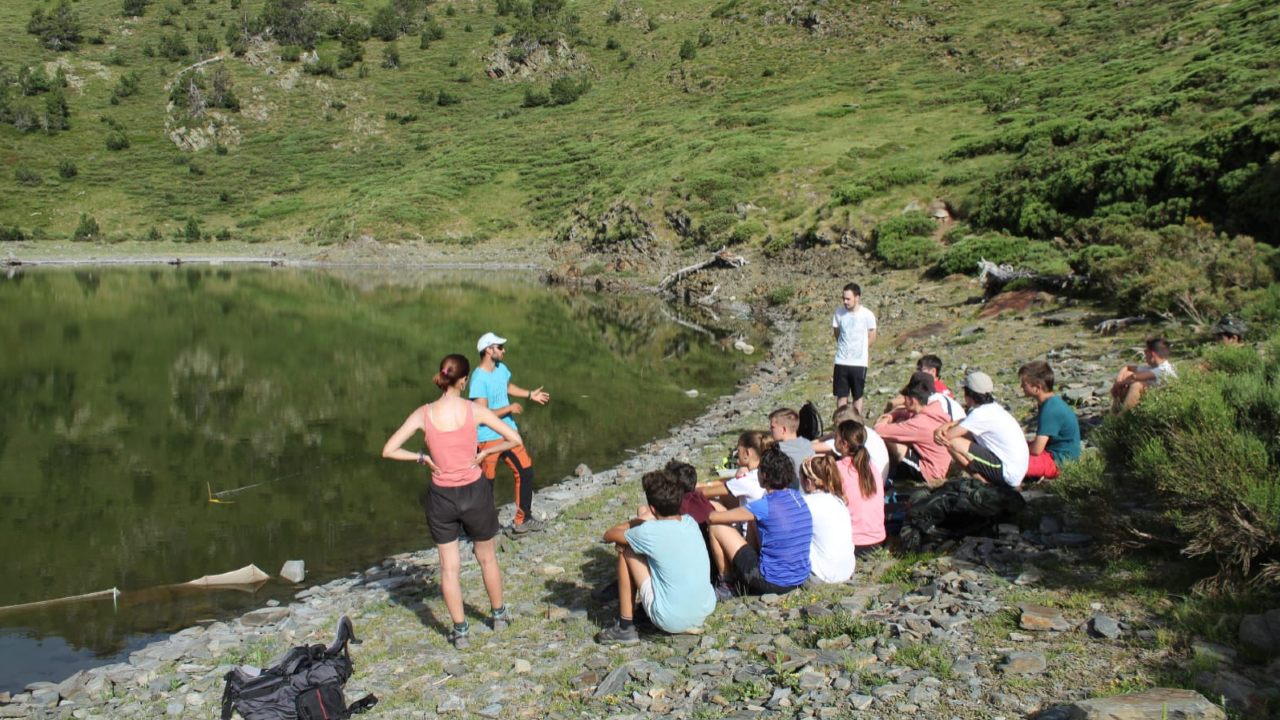 Un grup d'infants i joves a la vora d'un llac